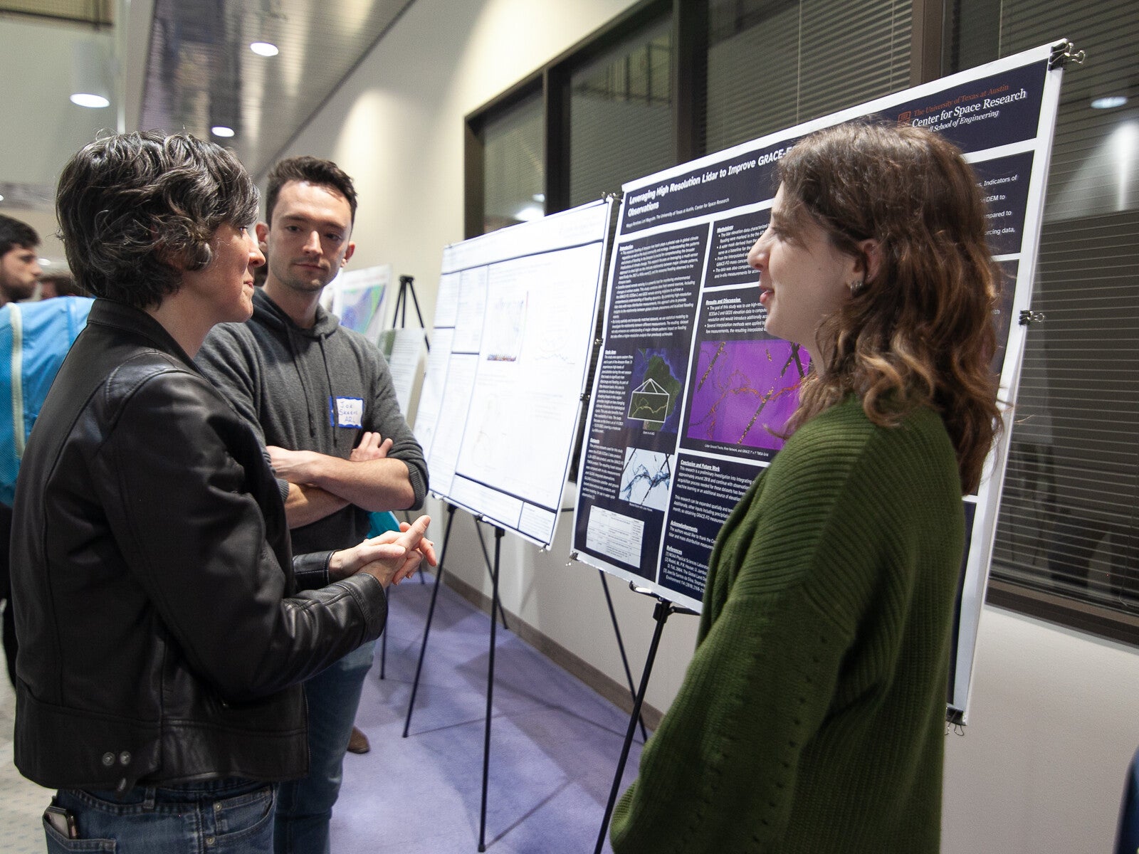 Three people talking in front of a scientific poster.
