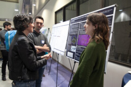 Three people talking in front of a scientific poster.